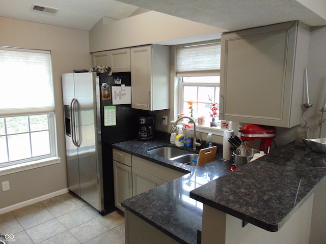 kitchen with visible vents, stainless steel refrigerator with ice dispenser, a sink, a textured ceiling, and a peninsula