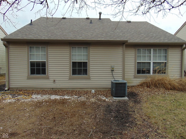 back of property with central AC and a shingled roof