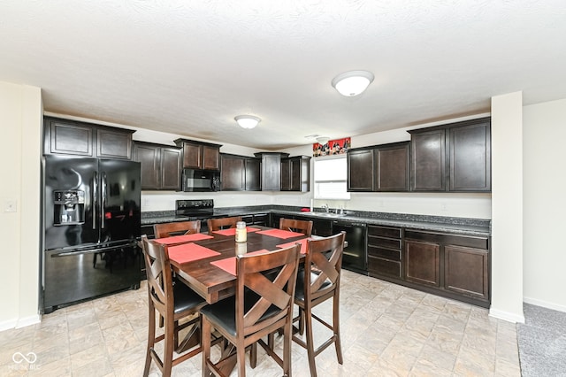 kitchen with baseboards, a sink, black appliances, dark brown cabinets, and dark countertops