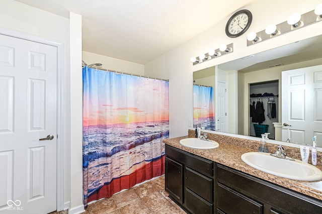 full bath featuring a sink, visible vents, a spacious closet, and double vanity