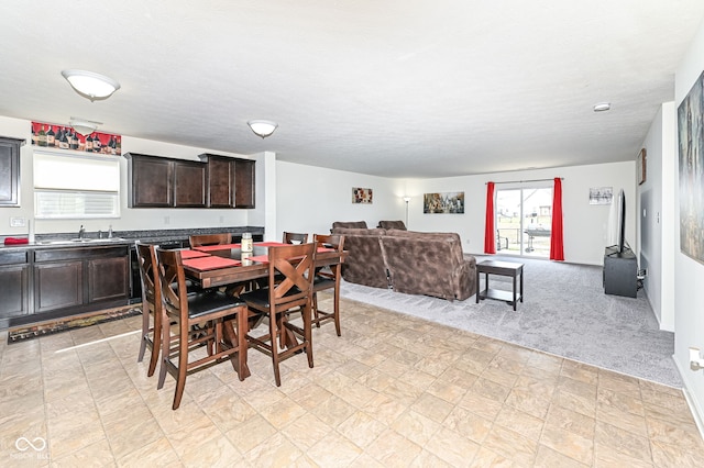 dining area featuring light colored carpet and a textured ceiling