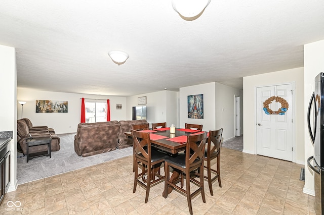 dining area featuring baseboards, light carpet, and a textured ceiling