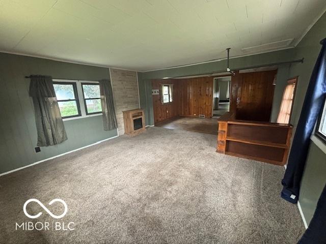 1713 Charles St, Lafayette, IN 47904 - unfurnished living room with carpet floors, wood walls, a fireplace, and baseboards