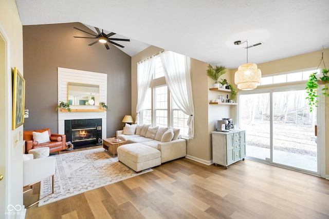 living room featuring visible vents, baseboards, a tile fireplace, ceiling fan, and light wood-style floors