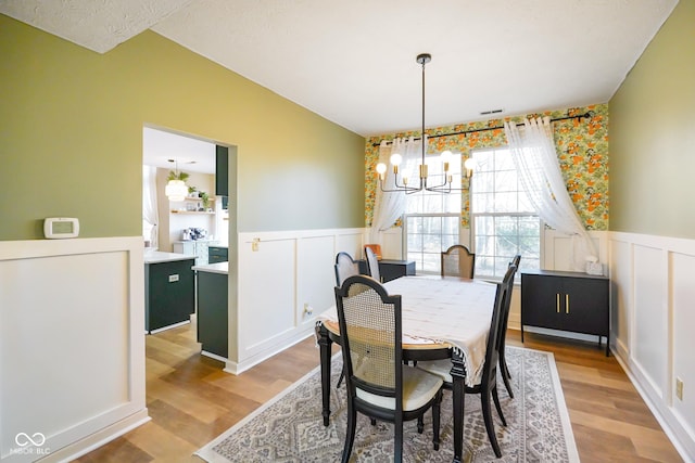 dining space featuring light wood-style floors, a notable chandelier, and wainscoting