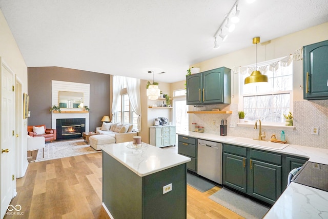 kitchen featuring a sink, a kitchen island, light wood-style floors, green cabinetry, and dishwasher