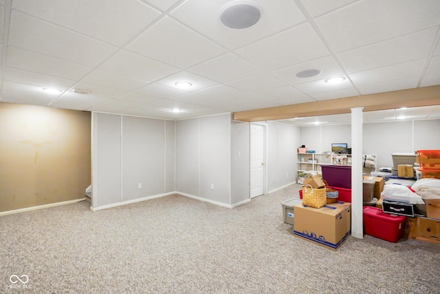 finished basement with a paneled ceiling, baseboards, and carpet floors