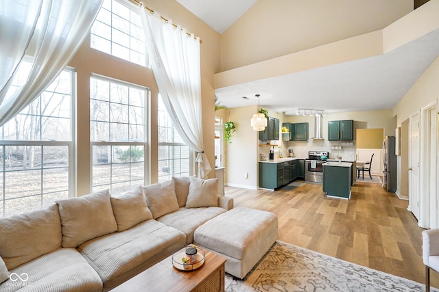 living room with light wood-style flooring, baseboards, a wealth of natural light, and high vaulted ceiling