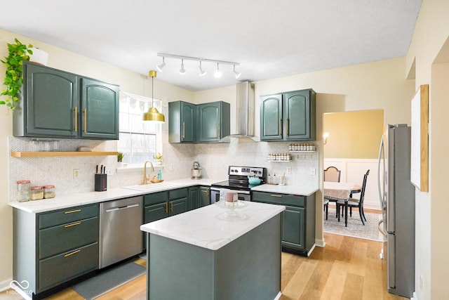 kitchen featuring light wood finished floors, green cabinets, light countertops, appliances with stainless steel finishes, and a sink