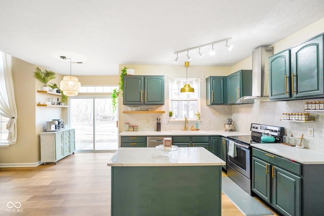 kitchen featuring a healthy amount of sunlight, appliances with stainless steel finishes, wall chimney range hood, and green cabinetry