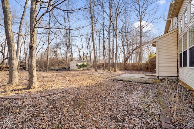 view of yard featuring a storage unit, a patio, an outbuilding, and fence