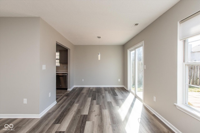 unfurnished room with dark wood finished floors, plenty of natural light, and baseboards