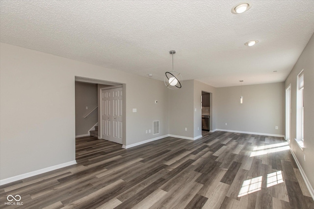 unfurnished living room featuring visible vents, baseboards, dark wood finished floors, and stairway