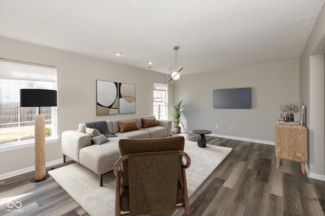 living area with baseboards, a textured ceiling, and dark wood finished floors