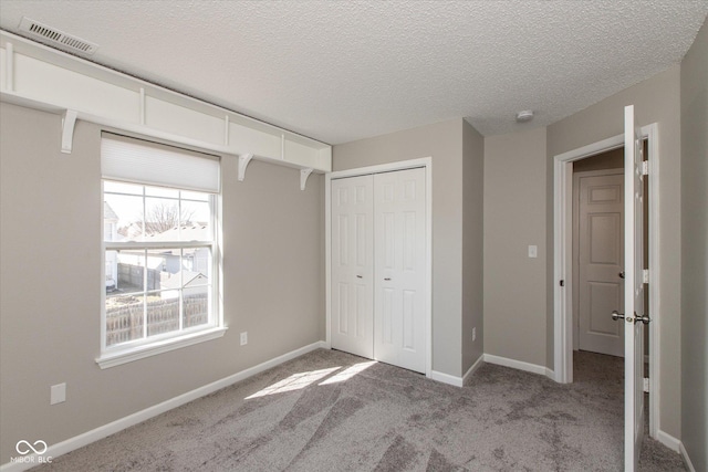 unfurnished bedroom featuring light carpet, visible vents, baseboards, and a closet