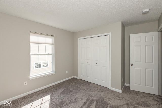 unfurnished bedroom featuring carpet flooring, baseboards, a closet, and a textured ceiling