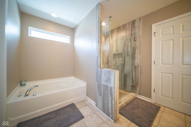 bathroom featuring tile patterned floors, baseboards, a garden tub, and a shower stall