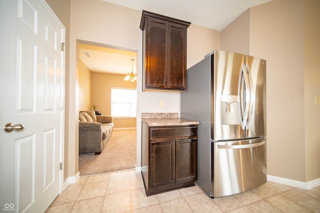 kitchen featuring baseboards, stainless steel fridge, dark brown cabinetry, and light countertops