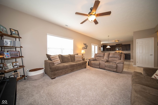 living room featuring visible vents, light colored carpet, and a ceiling fan