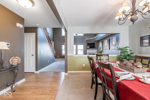 dining area with a textured ceiling, stairway, baseboards, and a chandelier