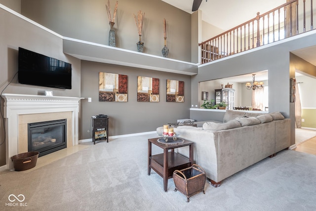 living area with baseboards, carpet floors, an inviting chandelier, a high ceiling, and a fireplace with flush hearth