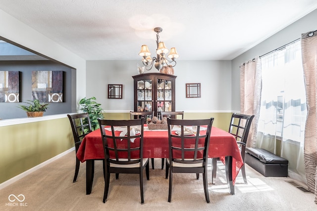 dining space featuring carpet, baseboards, visible vents, a textured ceiling, and a chandelier