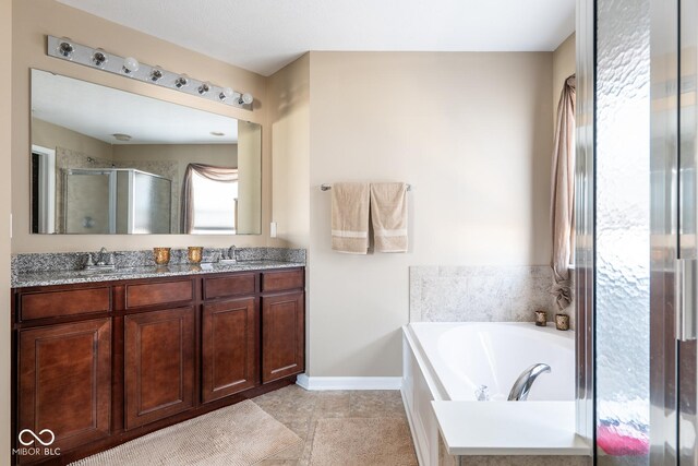 bathroom featuring a garden tub, a stall shower, a sink, double vanity, and baseboards