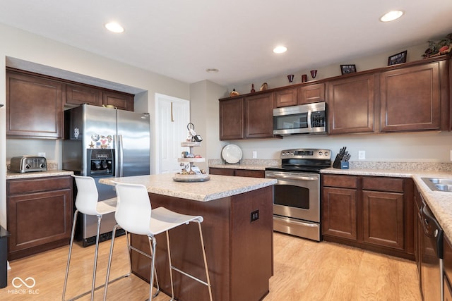 kitchen featuring recessed lighting, a kitchen island, appliances with stainless steel finishes, and light wood-style flooring