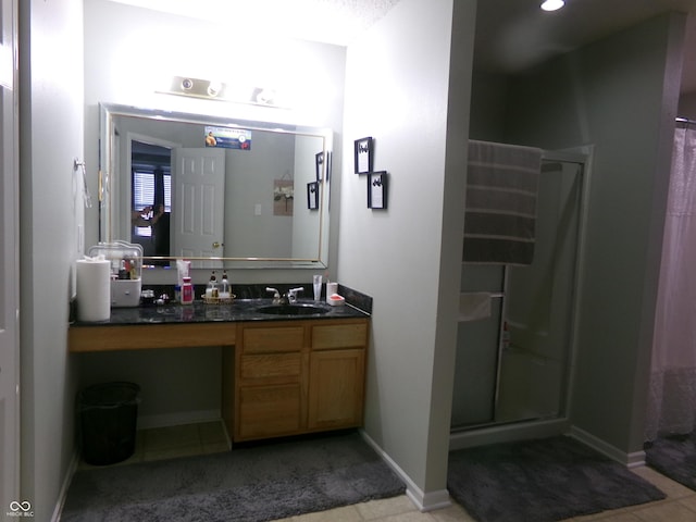 full bath with a stall shower, vanity, and baseboards