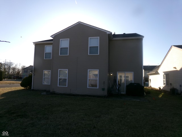 rear view of house featuring cooling unit and a lawn