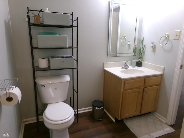 bathroom with baseboards, toilet, wood finished floors, and vanity