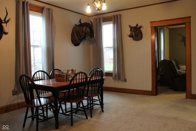 dining room featuring crown molding, a notable chandelier, baseboards, and light carpet