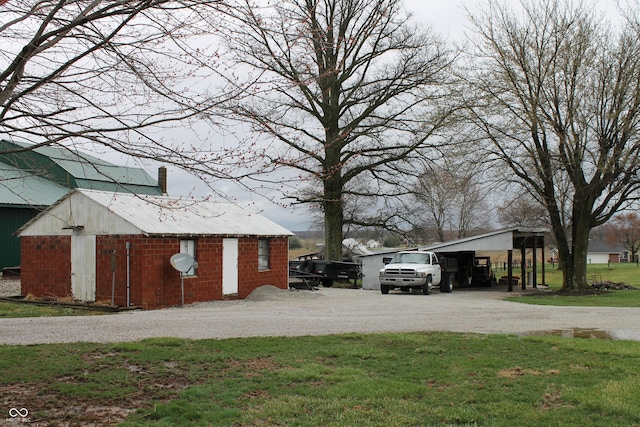 exterior space featuring a carport, an outdoor structure, a lawn, and driveway