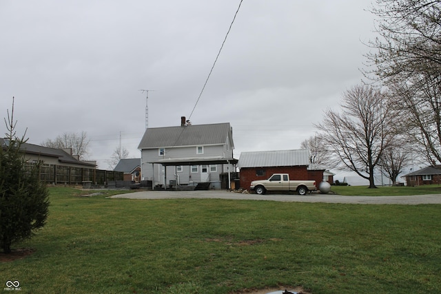 back of property with a yard, metal roof, a chimney, and fence