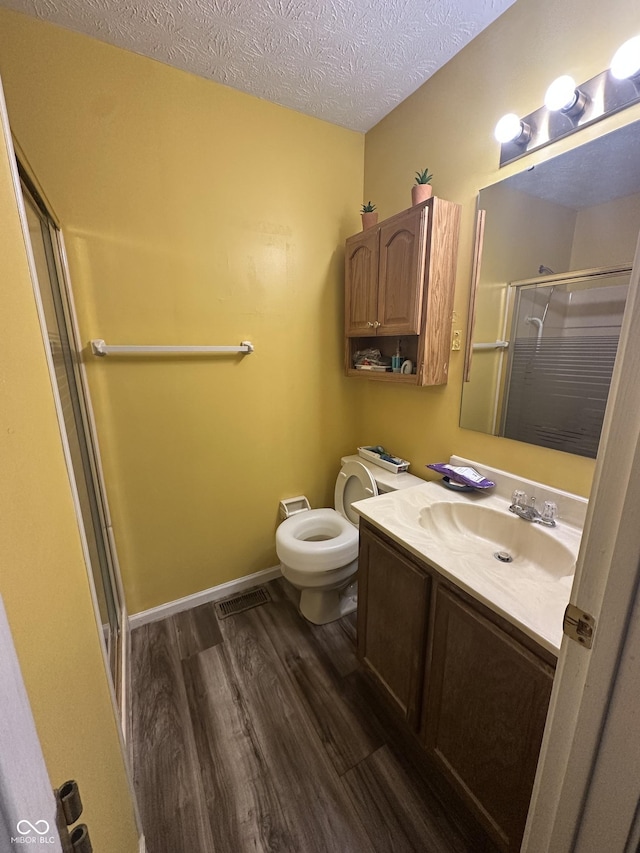 full bath with wood finished floors, visible vents, a shower stall, a textured ceiling, and toilet