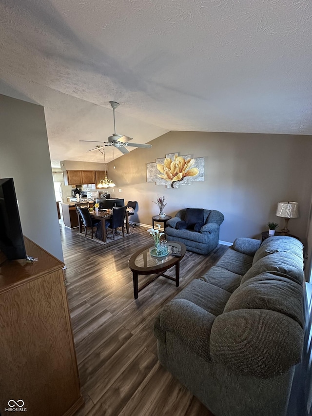 living room with lofted ceiling, a ceiling fan, a textured ceiling, baseboards, and dark wood-style flooring