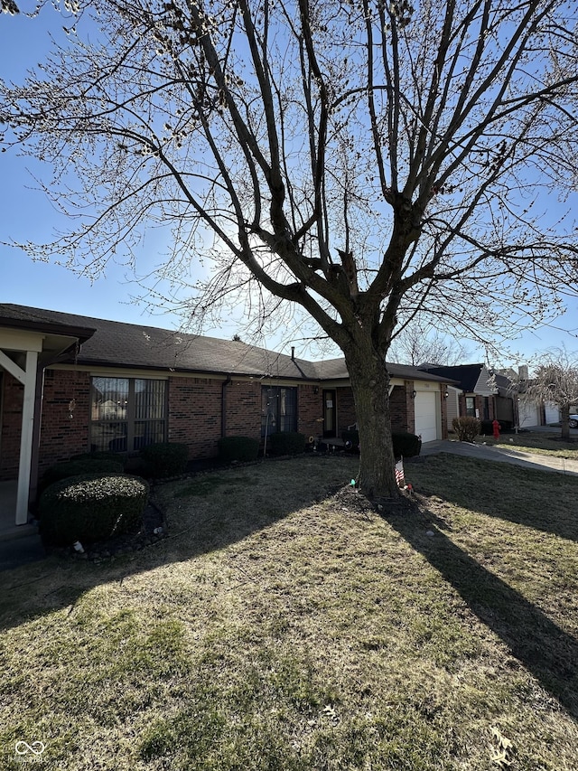 view of property exterior with a yard, brick siding, a garage, and driveway