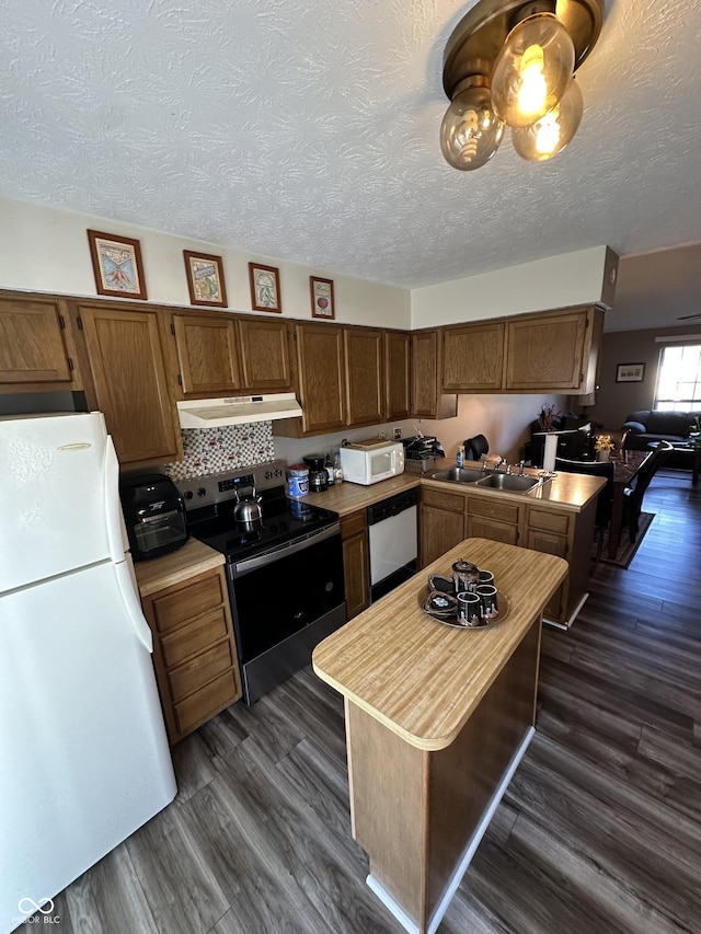 kitchen featuring a sink, under cabinet range hood, light countertops, white appliances, and dark wood-style flooring