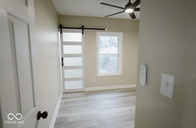 4504 Winthrop Ave, Indianapolis, IN 46205 - spare room featuring light wood finished floors, baseboards, ceiling fan, and a barn door