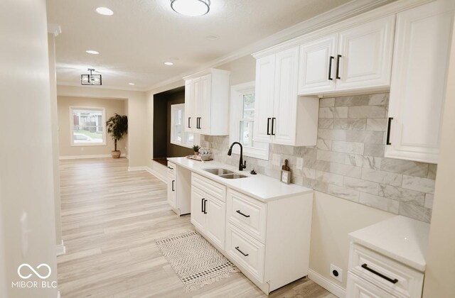 4504 Winthrop Ave, Indianapolis, IN 46205 - kitchen with a sink, white cabinets, light wood-style floors, backsplash, and baseboards