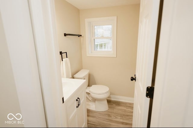 4504 Winthrop Ave, Indianapolis, IN 46205 - half bathroom featuring toilet, vanity, wood finished floors, and baseboards