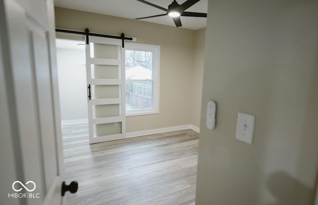 4504 Winthrop Ave, Indianapolis, IN 46205 - spare room with a barn door, light wood-style flooring, baseboards, and ceiling fan