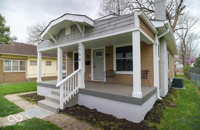 4504 Winthrop Ave, Indianapolis, IN 46205 - bungalow featuring a chimney, central AC unit, fence, and covered porch