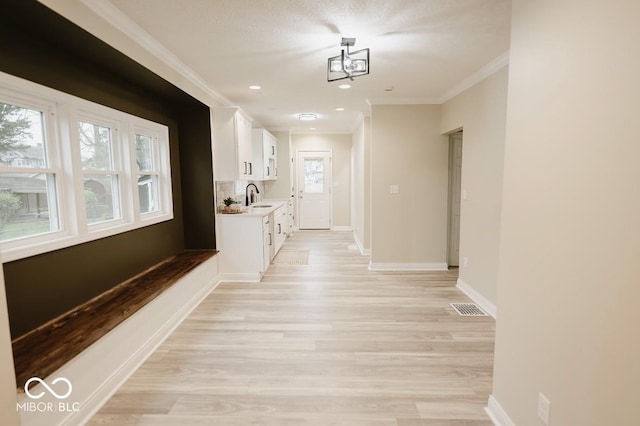 4504 Winthrop Ave, Indianapolis, IN 46205 - hallway with light wood-type flooring, visible vents, a sink, and crown molding
