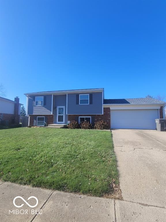 4930 Candy Spots Dr, Indianapolis, IN 46237 - split foyer home featuring concrete driveway, brick siding, a garage, and a front yard