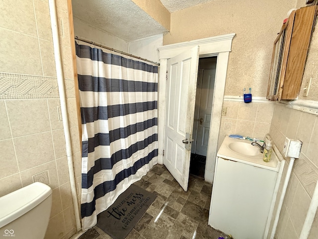 bathroom featuring vanity, a textured ceiling, curtained shower, tile walls, and toilet