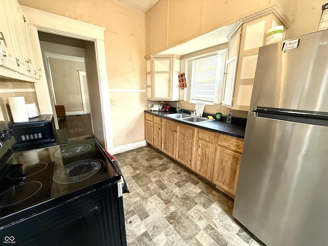 kitchen featuring dark countertops, baseboards, stone finish floor, black appliances, and a sink