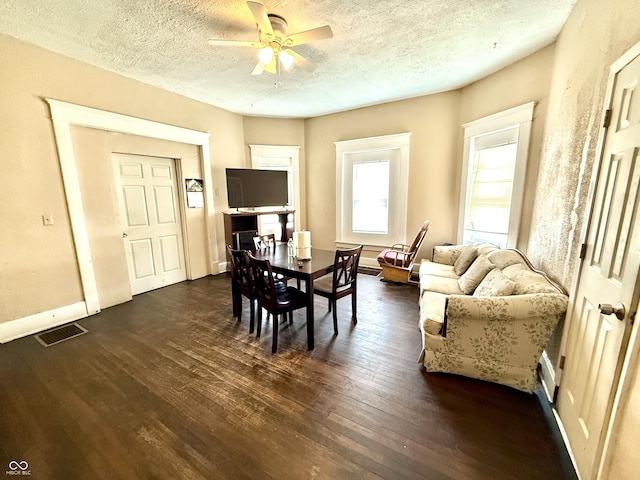 dining area featuring baseboards, visible vents, dark wood-style flooring, ceiling fan, and a textured ceiling