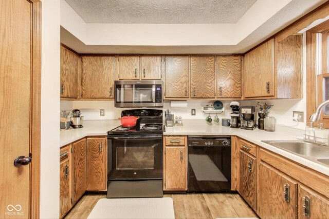 7152 Sandalwood Dr, Avon, IN 46123 - kitchen featuring a textured ceiling, light countertops, light wood finished floors, a sink, and black appliances