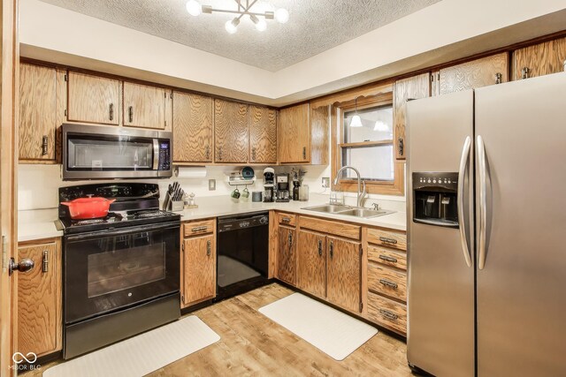 7152 Sandalwood Dr, Avon, IN 46123 - kitchen featuring light countertops, a sink, light wood-style flooring, black appliances, and an inviting chandelier